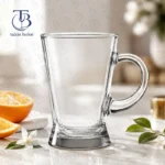 لیوان دسته دار شیشه ای از جنس بلور روی یک میز سفید