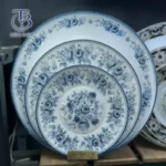 بشقاب سفید با طرح آبی روی تخته چوبی