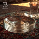 فنجان نعلبکی شیشه ای از جنس بلور روی فرش سنتی ایرانی و یک فنجان نعلبکی شیشه ای در داخل پس زمینه تصویر