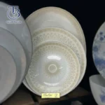 بشقاب سفید با طرح خورشیدی روی تخته چوبی بکگراند مشکی