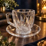 فنجان نعلبکی شیشه ای از جنس بلور روی یک میز چوبی