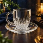 فنجان نعلبکی شیشه ای از جنس بلور روی یک میز چوبی