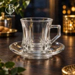 فنجان نعلبکی شیشه ای از جنس بلور روی یک میز چوبی