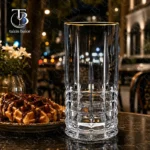 لیوان شربت خوری شیشه ای لب طلایی از جنس بلور روی یک میز