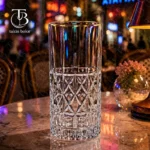 لیوان شربت خوری شیشه ای لب طلایی از جنس بلور روی یک میز