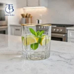 نیم لیوان شیشه ای از جنس بلور لب طلایی روی یک میز