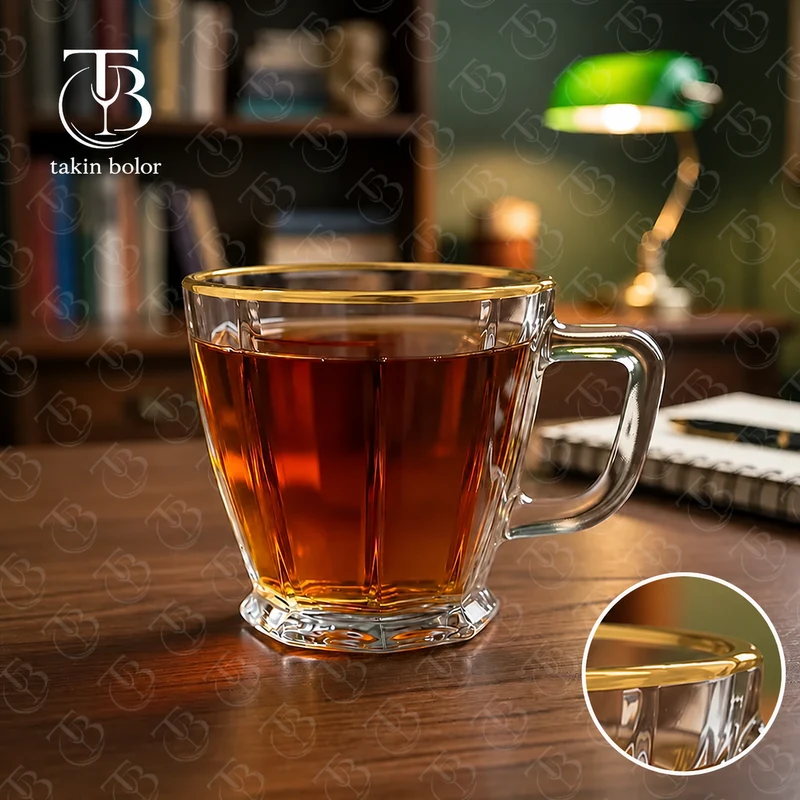 فنجان شیشه ای لب طلا از جنس بلور روی یک میز چوبی