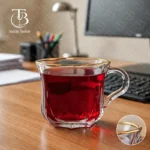 فنجان شیشه ای لب طلا از جنس بلور روی یک میز چوبی