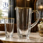 پارچ و لیوان شیشه ای لب طلا روی یک میز