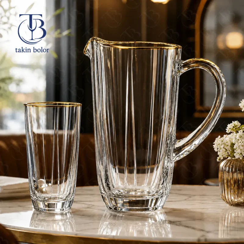 پارچ و لیوان شیشه ای لب طلا روی یک میز