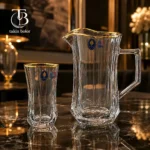 پارچ و لیوان شیشه ای لب طلا از جنس بلور روی یک میز