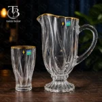 پارچ و لیوان شیشه ای لب طلا از جنس بلور روی یک میز