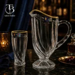 پارچ و لیوان شیشه ای لب طلا روی یک میز مشکی
