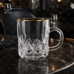 لیوان شیشه ای لب طلا از جنس بلور روی یک میز مشکی