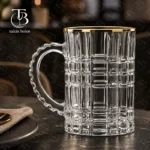 لیوان شیشه ای لب طلا از جنس بلور روی یک میز مشکی